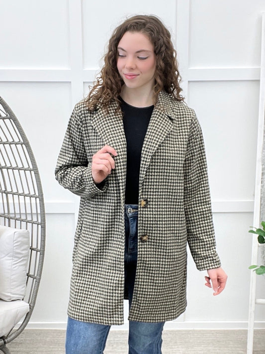 Women's black and cream houndstooth coat with notched lapel collar, button front closure, long sleeves, and side pockets.