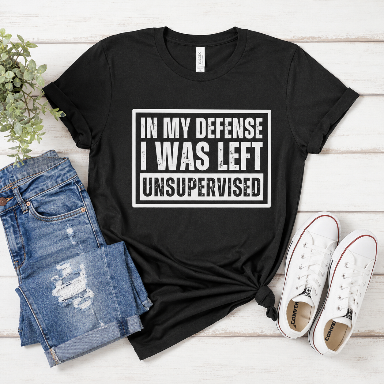 In My Defense I Was Left Unsupervised black Tultex graphic tee flat lay